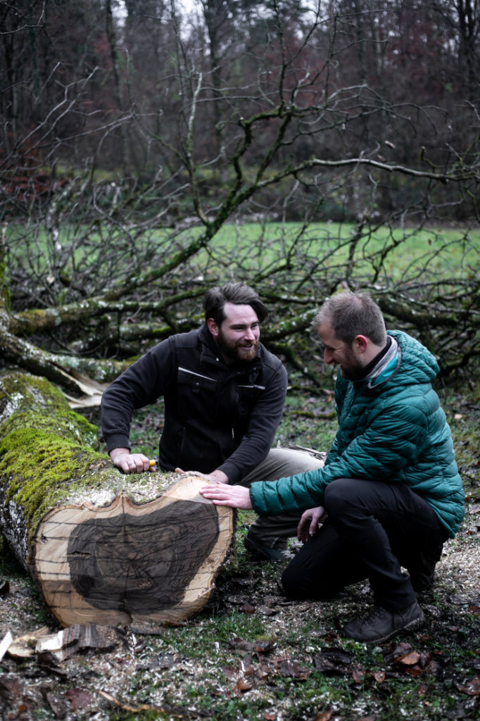 Der Schreiner und der Kunde begutachten das Holz des gefällten Baums