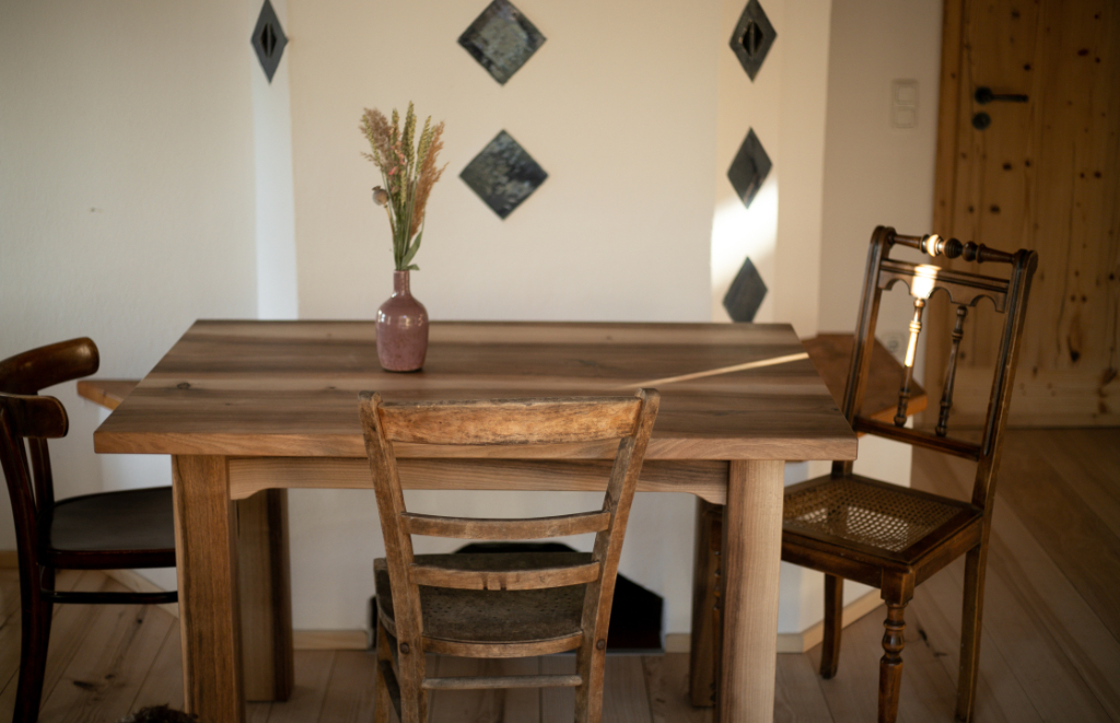 Der fertig geschreinerte Tisch steht in einem Wohnzimmer mit drei Stühlen